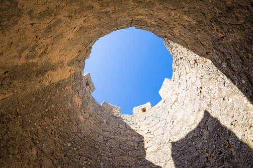 battlements of castle tower seen from below, as a circle with blue sky, in Penaranda de Duero village, landmark and public monument from eleventh century, in Burgos, Castile and Leon, Spain, Europe