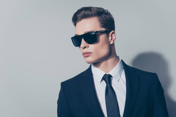 gros plan le portrait de l’homme séduisant élégant en costume noir et lunettes de soleil isolés sur fond gris - suit necktie close up gray photos et images de collection