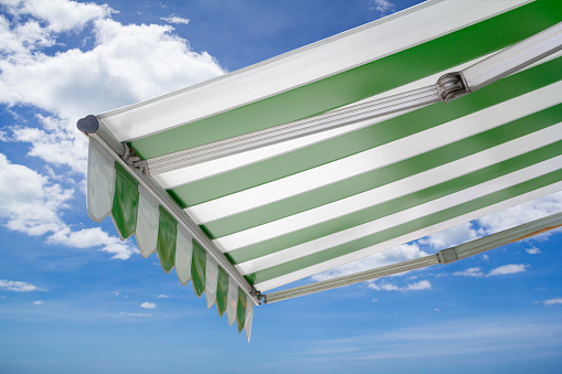 green and white striped awning against blue sky
