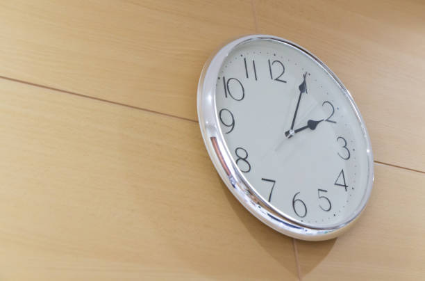 istock white steel clock on wooden wall in afternoon 936092590