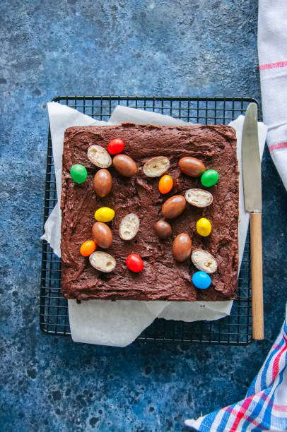 istock Dark chocolate brownie squares on a wire rack decorated with creamy chocolate eggs. Blue stone background. 936093138