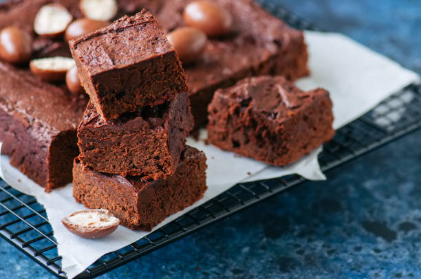 istock Dark chocolate brownie squares on a wire rack decorated with creamy chocolate eggs. Blue stone background. 936093154