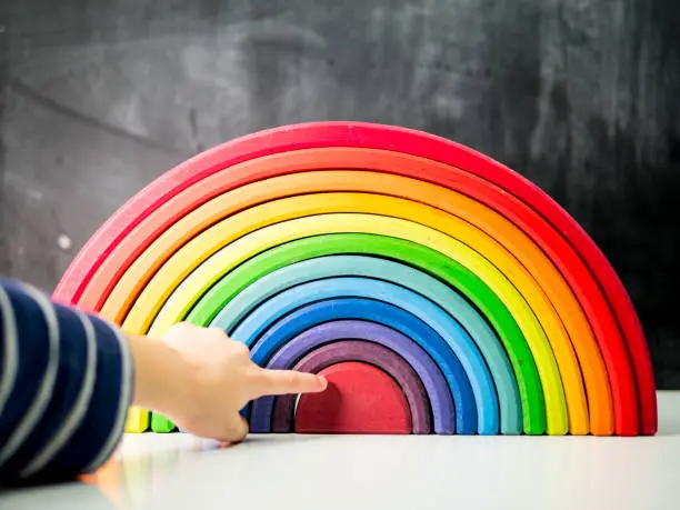 Child pointing at centre of wooden rainbow