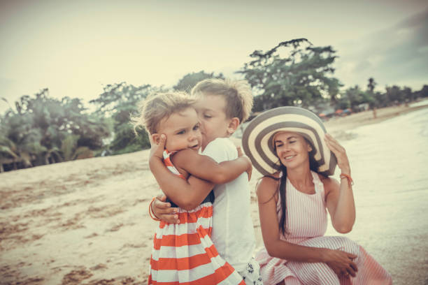 Rear view of happy kids at the beach with hands raised.