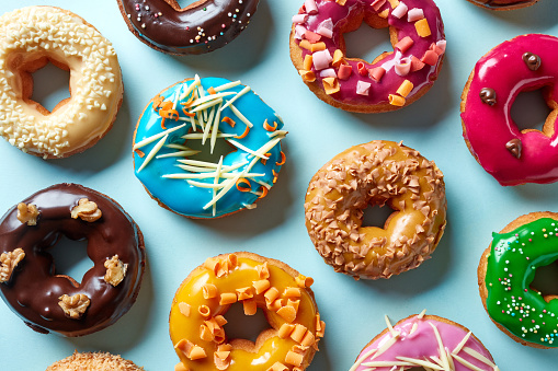 Various colorful donuts on blue background, top view