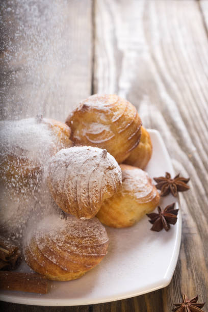 istock Delicious eclairs sprinkled with icing sugar, stand on a wooden table. Copy spase. 936109616