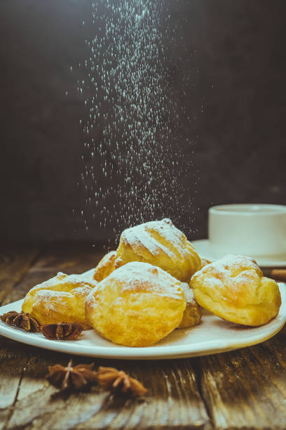 istock Delicious eclairs sprinkled with icing sugar, stand on a wooden table. Copy spase. 936110546