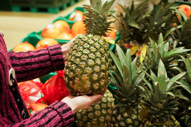 Woman chooses pineapple in a supermarket.