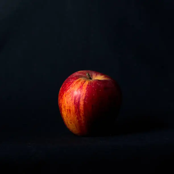 Red apple on black background and side light