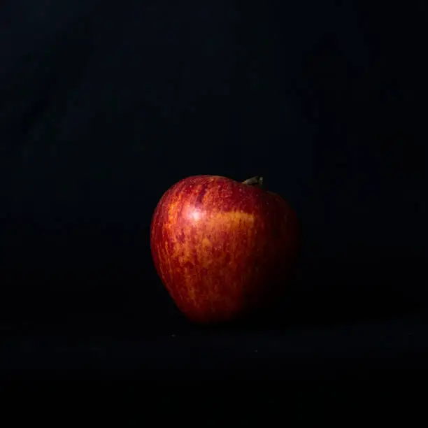 Red apple on black background and side light