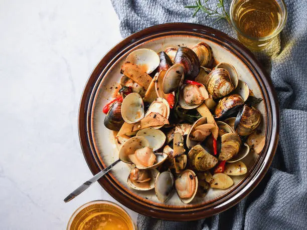 Stir-frying Ginger and clams at high heat to bring forth the savory aroma with sesame oil in recipe