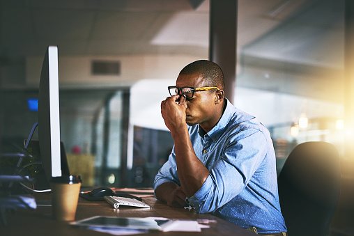 Shot of a young businessman experiencing stress during late night at work