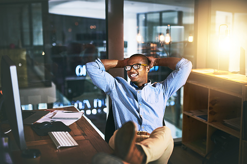 Shot of a young businessman relaxing at his desk during a late night at work