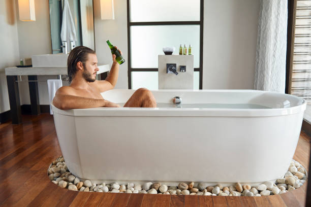 istock young handsome man enjoying in the bathtub and having a beer 936120706