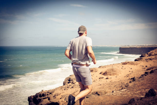 istock Sportsman running at the beach coast. From back. 936129362