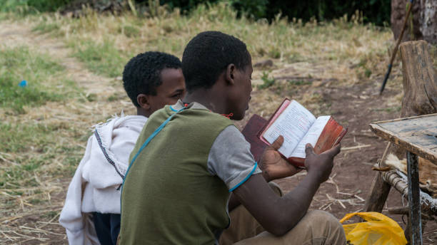 Unidentified pilgrim reading bible at one of the old rock churches from Lalibela Lalibela, Ethiopia - September 2017: Unidentified pilgrim reading bible at one of the old rock churches from Lalibela ethiopian orthodox church stock pictures, royalty-free photos & images
