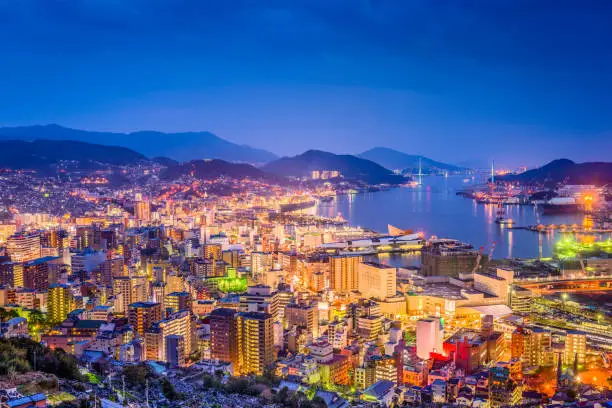 Nagasaki, Japan downtown skyline over the bay from above at night.