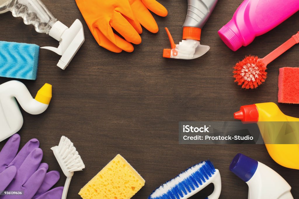 Various cleaning supplies, housekeeping background Spring cleaning background. Assortment of colorful spray detergents, sponges, rags and other supplies on wooden table, top view. Cleaning services and tidying up concept, copy space Cleaning Stock Photo