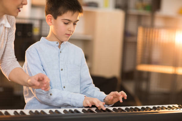 istock Teacher and a boy playing stage piano indoors 936139702