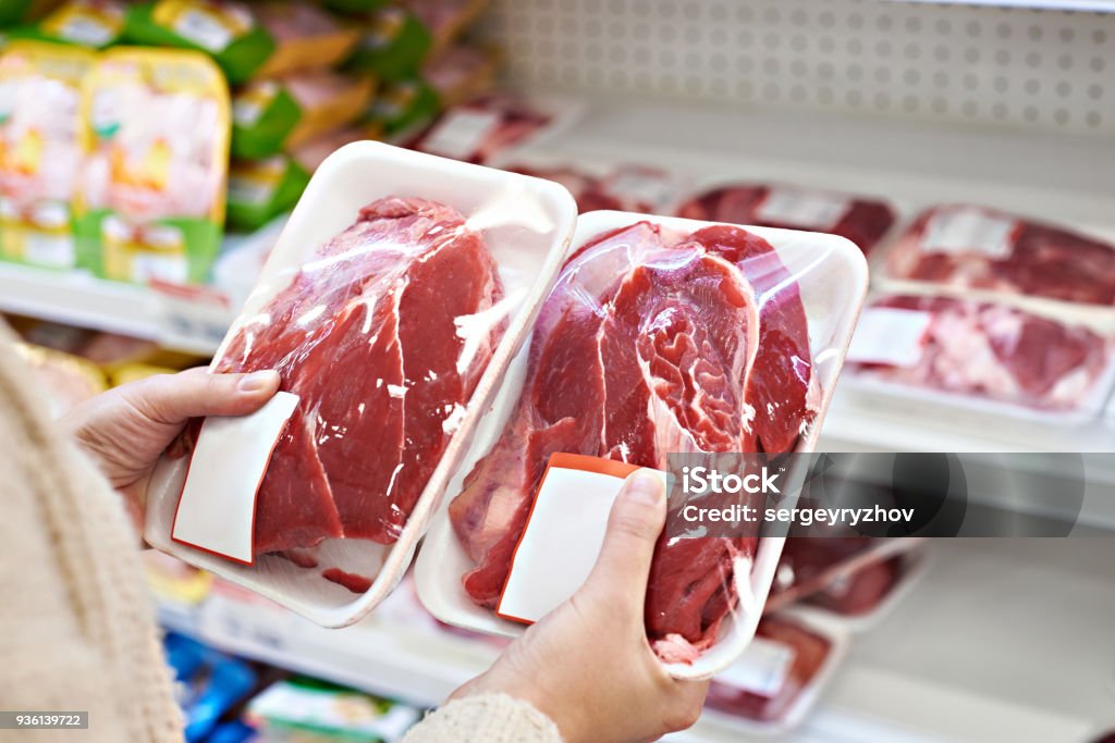 Buyer hands with beef meat packages at grocery Buyer hands with beef meat packages at the grocery store Meat Stock Photo