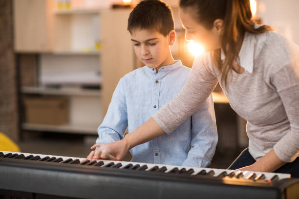 istock Teacher and a boy playing stage piano indoors 936139812