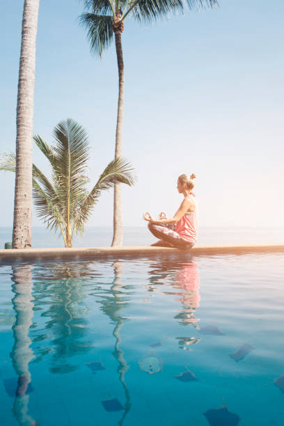 istock Beautiful woman practicing yoga at the pool 936143106