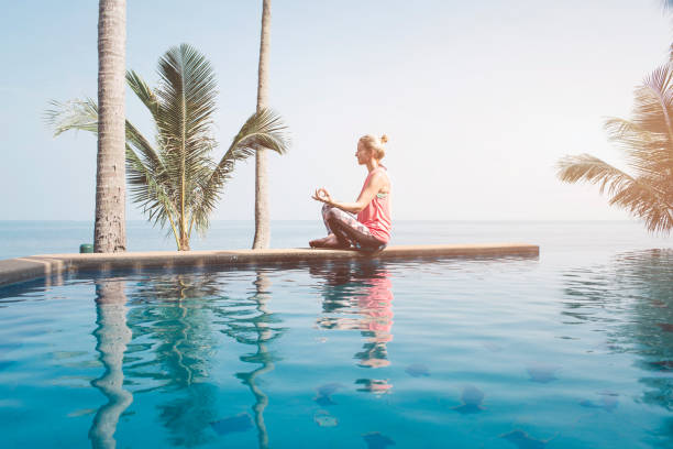 istock Beautiful woman practicing yoga at the pool 936143110