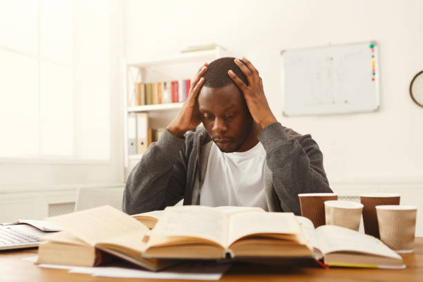 istock Black male student studying at table full of books 936144548