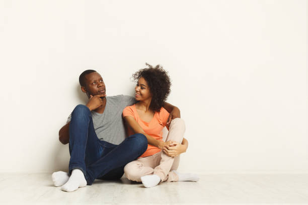 istock African-american couple hugging, sitting on floor 936144772
