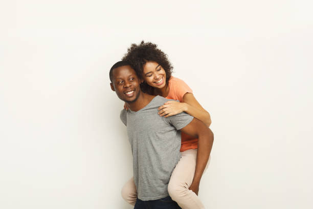 istock Black man piggybacking girlfriend at white studio 936147506