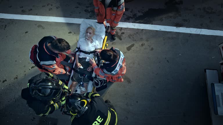 CS Paramedics securing the injured woman on the stretcher for transport with the help of the firemen