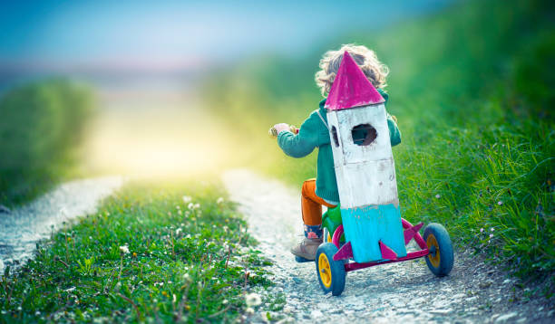 Child on Tricycle Carrying a Toy Space Rocket Child  Carrying a Toy Space Rocket tricycle stock pictures, royalty-free photos & images