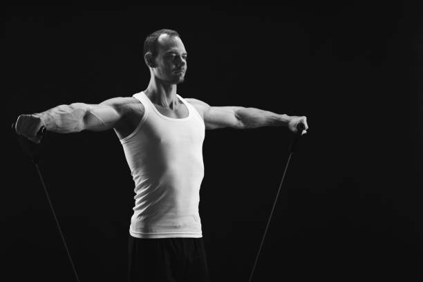 istock Athletic muscular man exercising with elastic expander at black 936160822