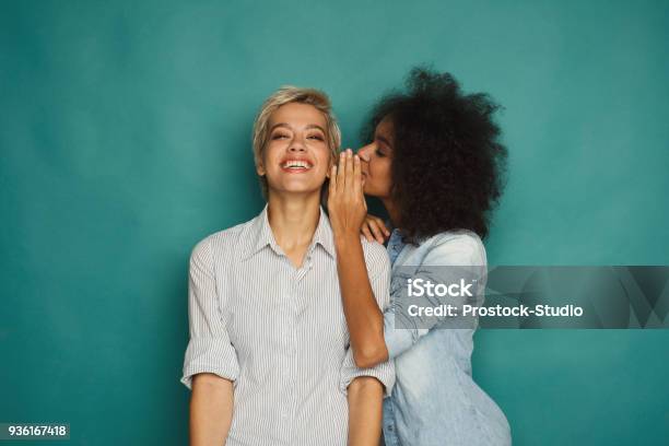 Photo libre de droit de Jeune Femme En Disant À Son Amie Quelques Secrets banque d'images et plus d'images libres de droit de Chuchoter à l'oreille - Chuchoter à l'oreille, Femmes, Amitié