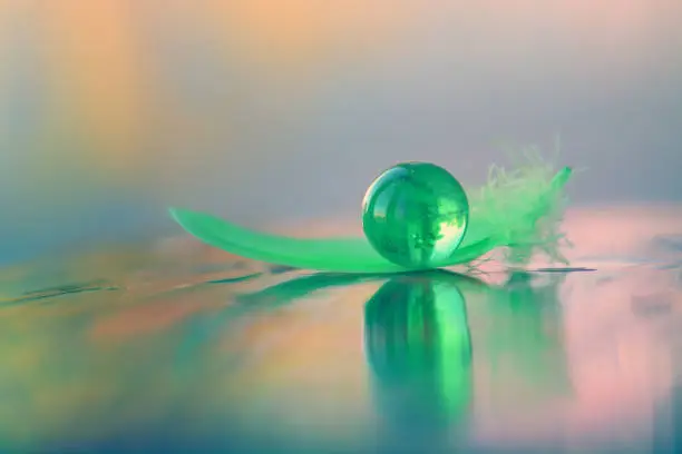Photo of Marble ball and feather in green color