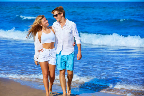 Blond young couple walking in the beach shore