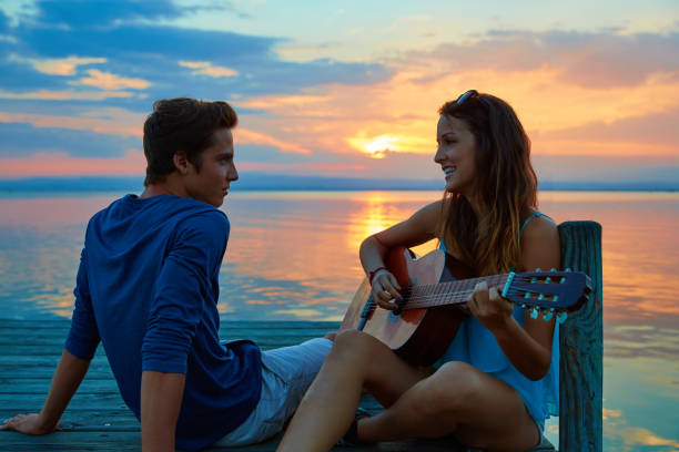 istock Couple playing guitar in sunset pier at dusk beach 936171604