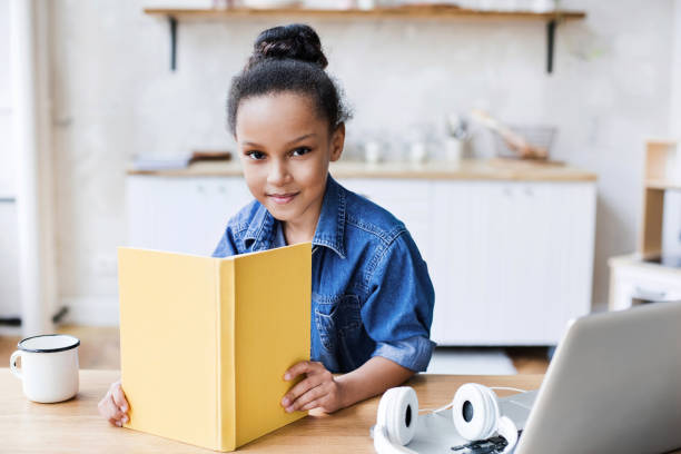 mała dziewczynka czyta książkę w domu - wireless technology serious education enjoyment zdjęcia i obrazy z banku zdjęć