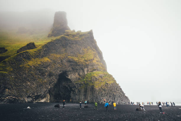 Reynisfjara Beach, Iceland - September 9, 2017: Tourists watching bird cliffs and cave Halsanefshellir on the famous black-sand beach Reynisfjara.