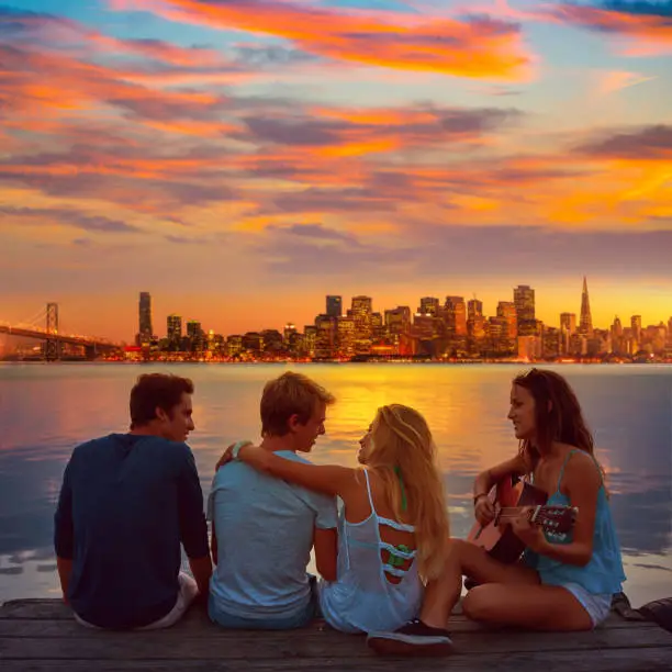 Friends group playing guitar in sunset pier at dusk in San francisco photo mount