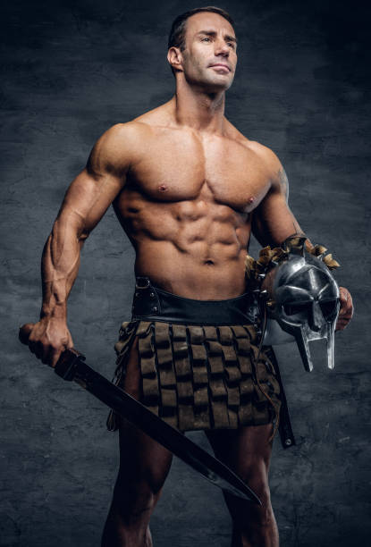 istock Middle age, muscular male holds silver gladiator helmet and an i 936177258