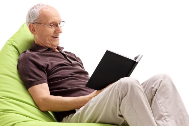 istock Senior seated on a beanbag reading a book 936177578