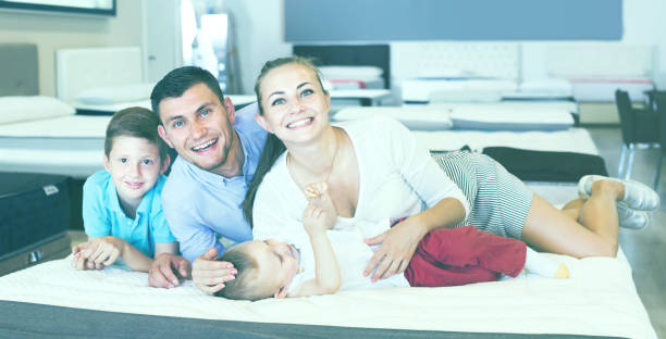 istock parents with two young sons testing mattress in store 936183082