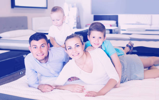 istock parents with two young sons testing mattress in store 936183116