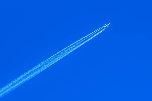istock Modern jet plane with white condensation track flies on a blue sky background 936183140