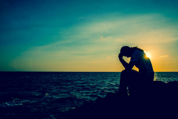 istock Silhouette women sitting alone on the rock. Sad and lonely. 936183250