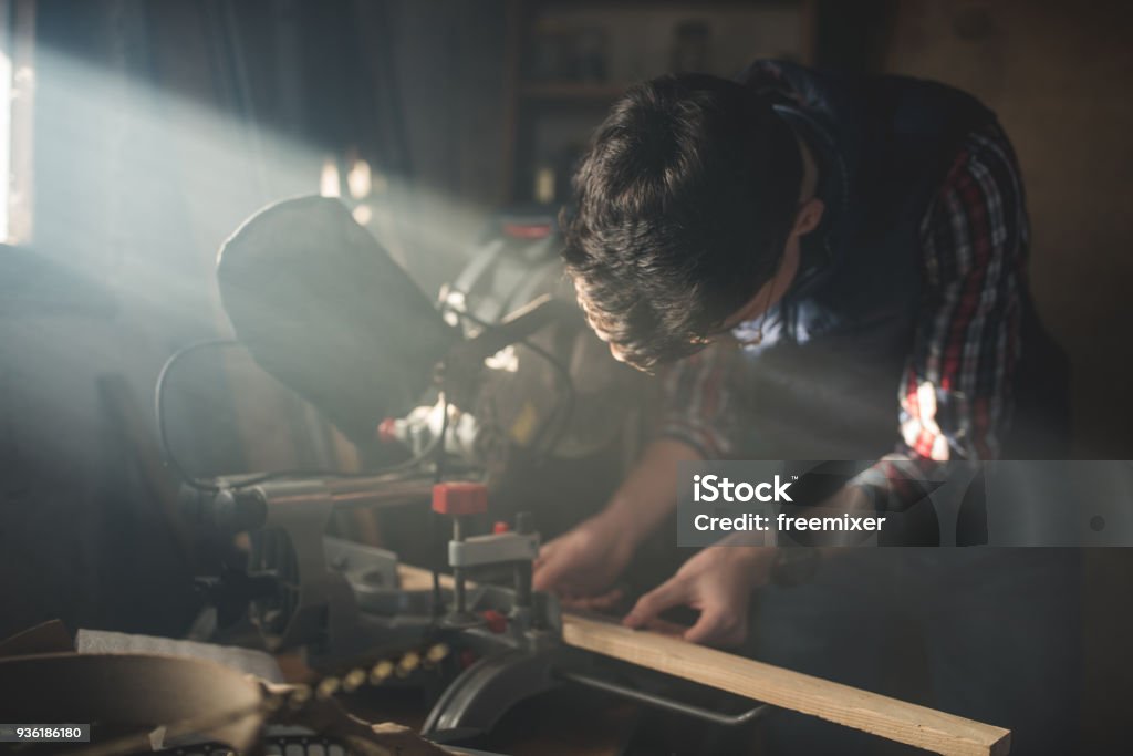 Young carpenter working Young carpenter cutting wood in his small work shop Adult Stock Photo