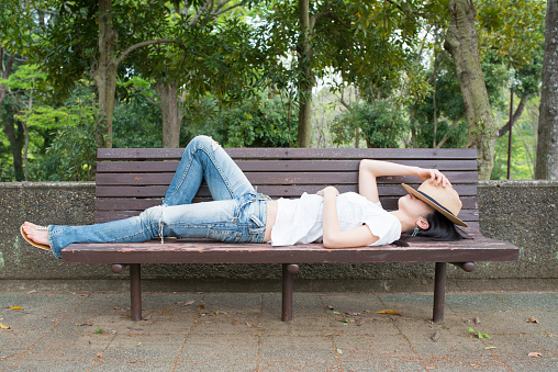 A Japanese woman is taking a nap on the park bench