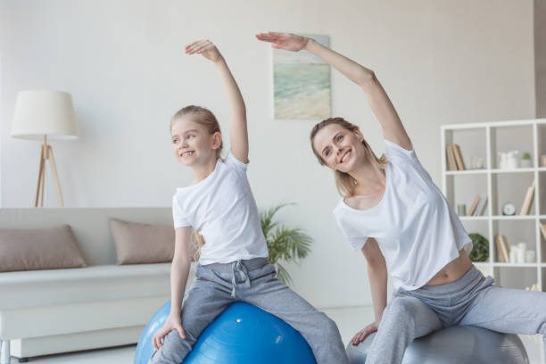 istock mother and daughter doing side bends on fit balls 936199350