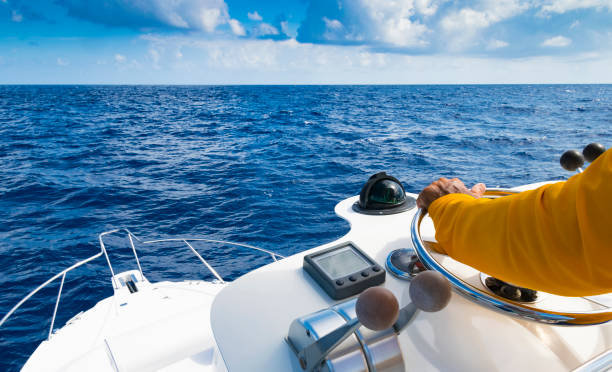 Hand of captain on steering wheel of motor boat in the blue ocean during the fishery day. Success fishing concept. Ocean yacht Hand of captain on steering wheel of motor boat in the blue ocean during the fishery day. Success fishing concept. Ocean yacht team captain stock pictures, royalty-free photos & images